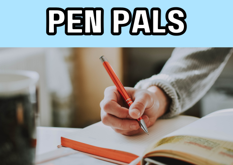 The image shows a hand writing on a piece of paper.