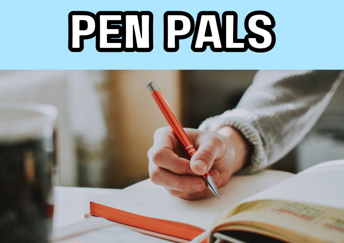 The image shows a hand writing on a piece of paper.